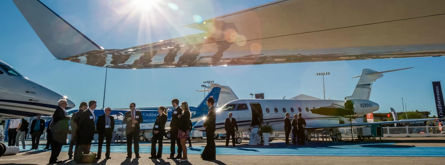 Students, Instructors, Business Professionals and Pilots congregate around planes on an airport runway