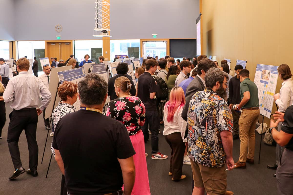 Dozens of people in a room with research posters