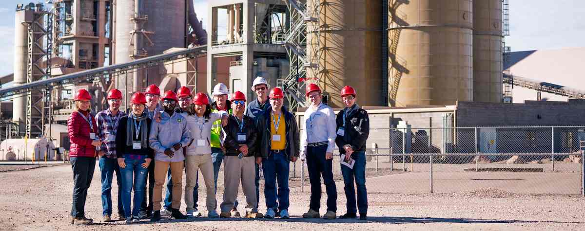 Students stand outside a cement manufacturing plant during an on site business consultation 