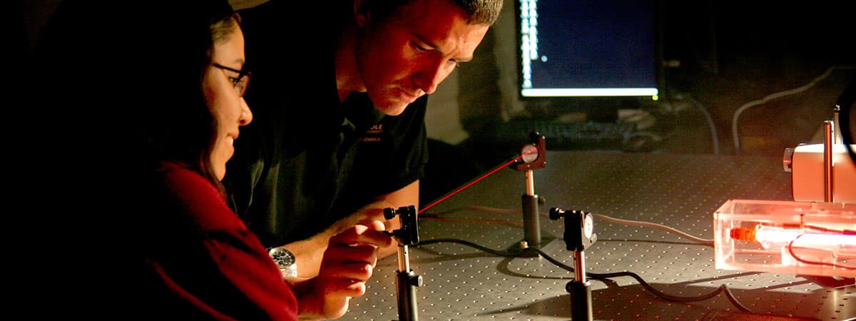 Two students experiment with laser light detection equipment in a laboratory