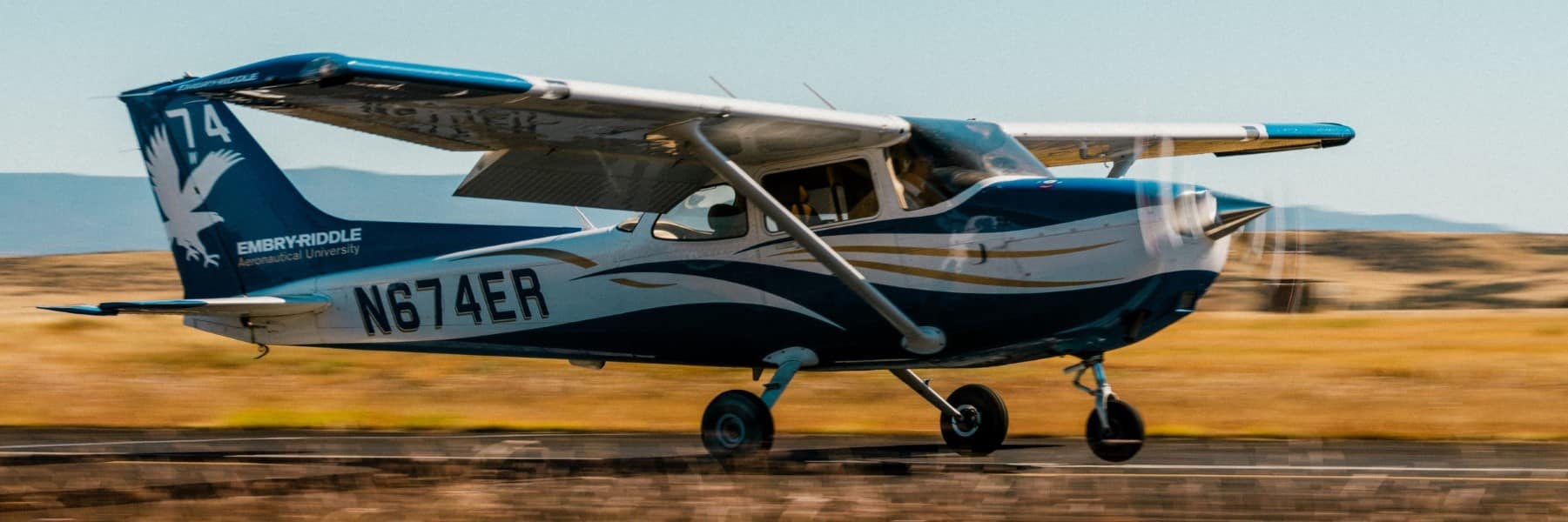 A low-flying propeller plane racing across a desert landscape.