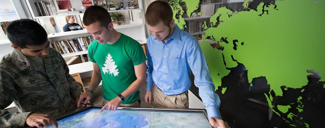 Three male students review a map. 