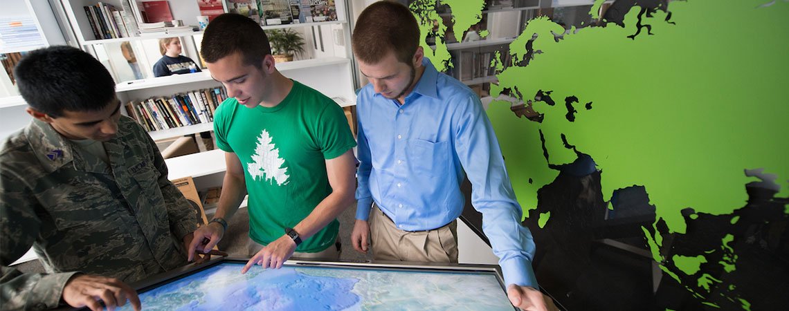 Three male students review a map.
