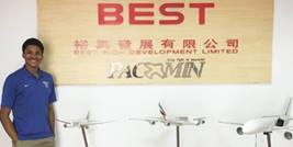 Study Abroad student stands in front of a sign with Chinese characters beside three model commercial aircraft