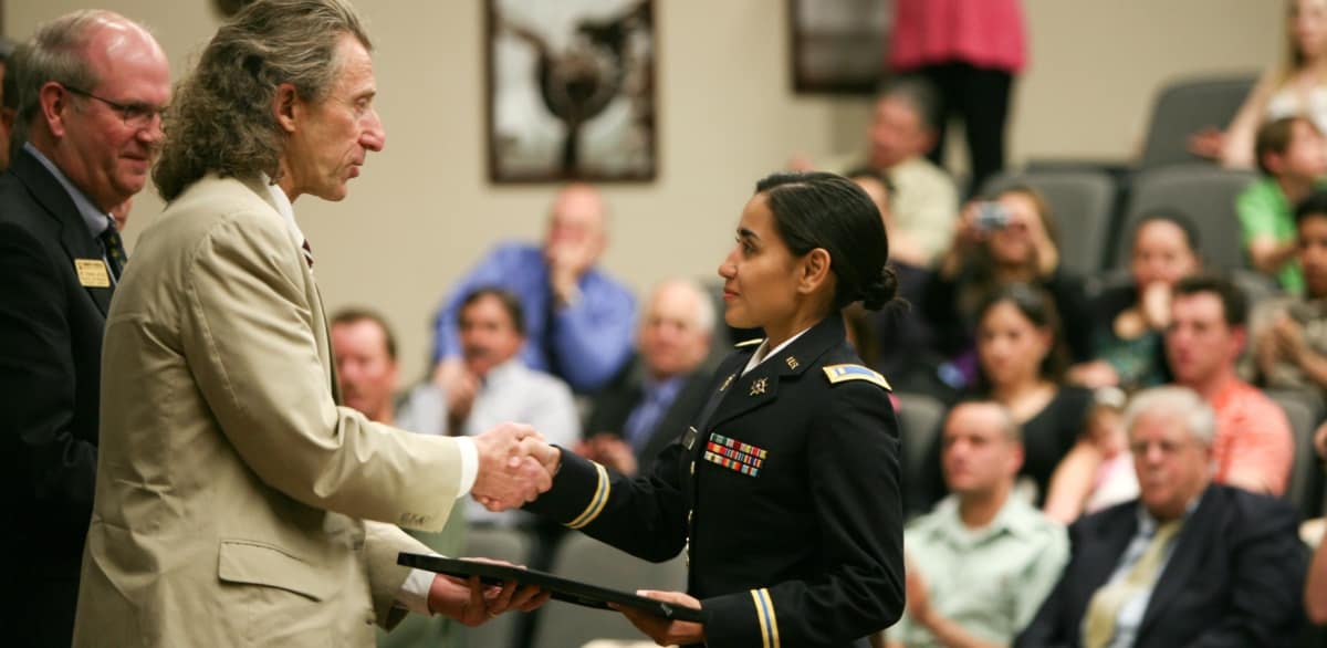An award is presented to a soldier on stage in the Davis Learning Center auditorium