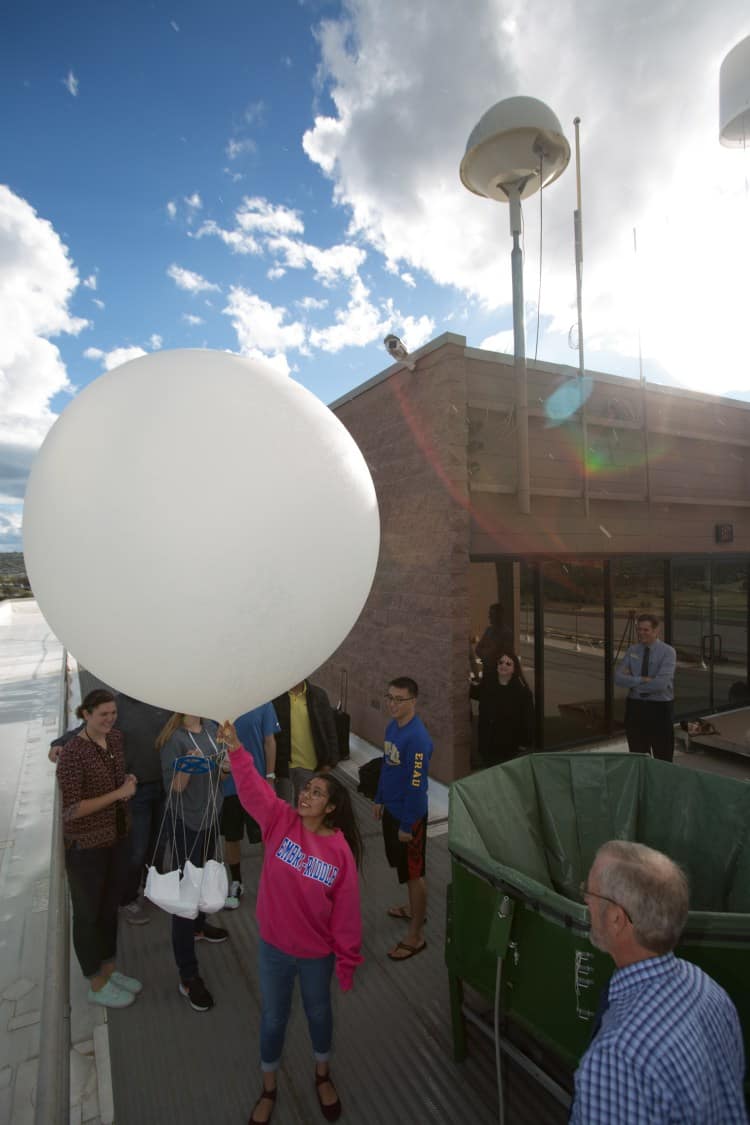 A student launches a weather balloon from the rooftop observation deck